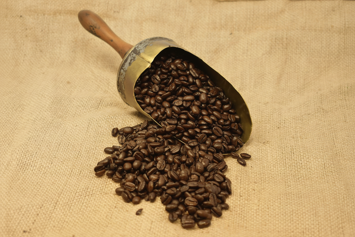 Sumatra Lintong dark roast coffee beans spilling from an antique brass scoop on hessian fabric